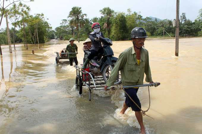 Người dân thôn Phú Thiện, xã Các Sơn, huyện Tĩnh Gia (Thanh Hóa) làm “dịch vụ” chở người, xe qua điểm ngập lụt trên tỉnh lộ 512 - Ảnh: Hà Đồng chụp chiều 2/10