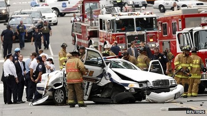 Nhân viên cứu hộ bên cạnh chiếc xe cảnh sát bị hư hại sau vụ rượt đuổi