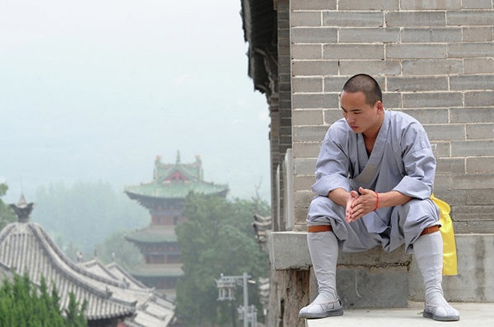 Một nhà sư và khung cảnh hoàng tráng phía sau của chùa Thiếu Lâm