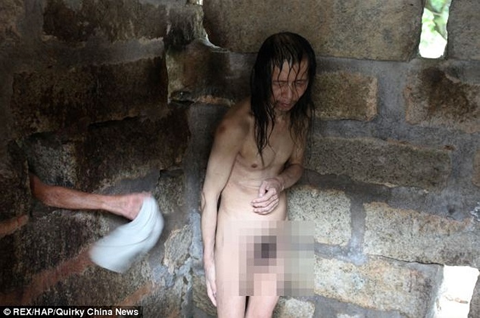 Bà Xiao Hong tắm rửa cho người con trai Dong Hai của mình qua một lỗ hổng trên bức tường chiếc cũi đá