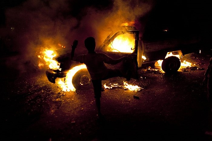 Người biểu tình đang sút vào chiếc xe cảnh sát bốc cháy tại Cairo, Ai Cập