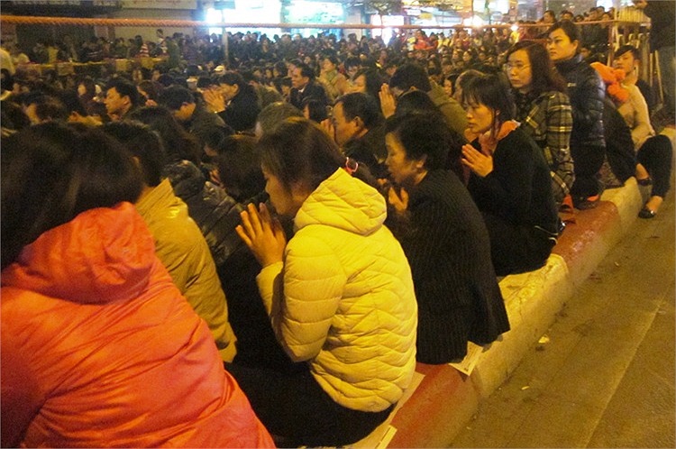 Số khác ngồi tràn lên lan can cầu vượt, mặt hướng về cổng chùa.