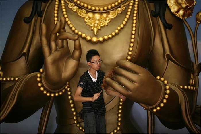 Cậu bé người Hoa ở Medan, Indonesia đang lau chùi tượng Phật trong đền thờ trước thềm năm mới âm lịch