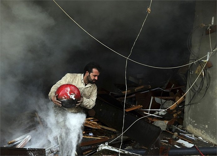 Người đàn ông chạy ra khỏi tòa nhà trúng tên lửa trong cuộc không kích của Không quân Syria ở thành phố Ain Tarma