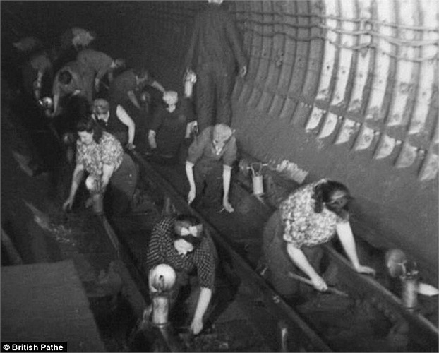 Những phụ nữ đang dùng dầu mỡ để lau các đoạn đường ray trong hầm