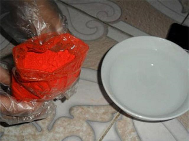 Sau đó cho một ít bột phẩm màu hoa hiên vào bát nước và hòa tan.