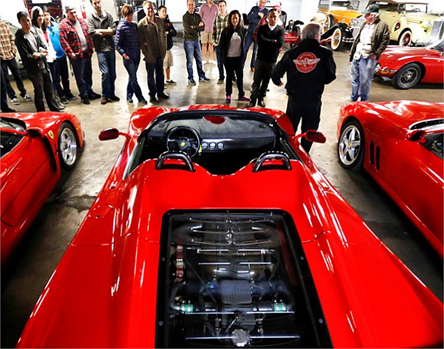 Hướng dẫn viên bảo tàng đang giới thiệu với khách tham quan bộ ba xe Ferrari đỏ. 