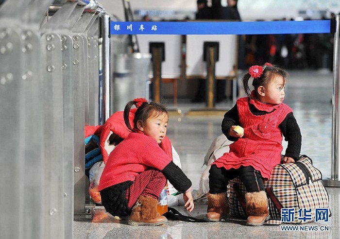 Những em nhỏ ngồi chờ bố mẹ làm thủ tục ở nhà ga