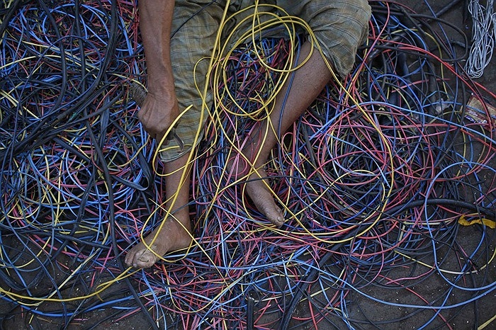 Người đàn ông đang thu thập đồng từ các dây cáp đã qua sử dụng trong một khu ổ chuột ở Mumbai, Ấn Độ