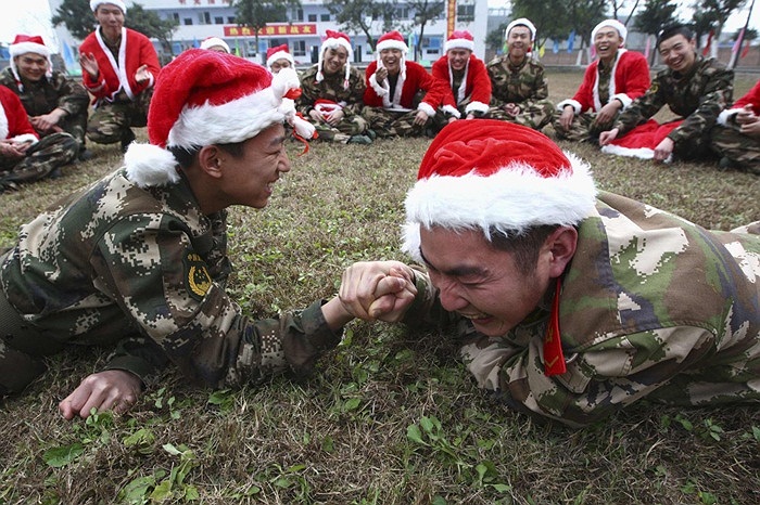 Binh sĩ lực lượng bán vũ trang ở Tứ Xuyên, Trung Quốc chơi vật tay trong khi đội mũ ông già Noel