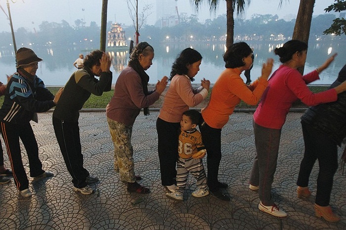 Cậu bé chơi đùa trong khi những người xung quanh tập thể dục ở ven hồ Gươm