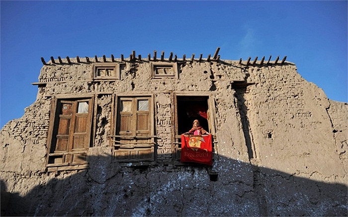 Cô gái Afghanistan nhìn qua cửa sổ nhà mình