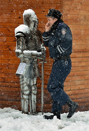 Nhân viên cảnh sát trò chuyện qua di động khi đi ngang qua bộ giáp trang trí tại một cửa hàng ở Kiev, Ukraine