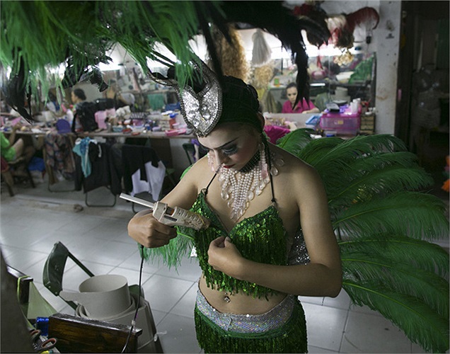 Một vũ công chuyển giới dùng súng bắn keo để tranh thủ sửa sang lại chiếc áo ngực thêm chắc chắn.