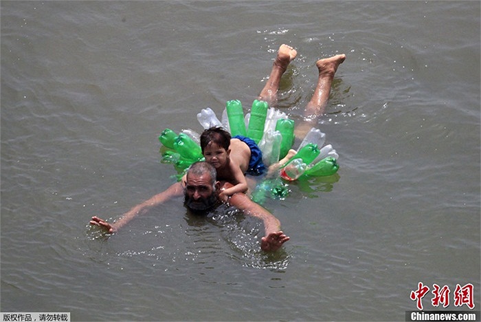 Hai cha con bơi bằng phao được làm từ chai nhựa ở vùng ngoại ô Lahore, Pakistan