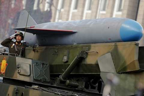 Một người lính Triều Tiên đứng chào trên chiếc xe chở tên lửa trong một cuộc diễu binh quân sự.