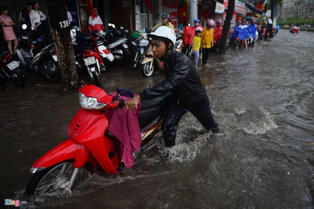 Nhiều xe chết máy phải dắt bộ trên đoạn đường ngập nước .