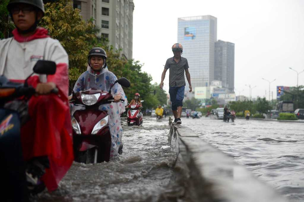 Để tránh nước ngập một thanh niên phải đi bộ trên con lươn phân cách làn xe . 