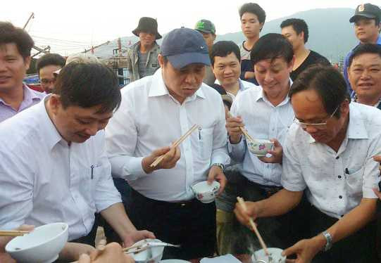 Chủ tịch UBND TP Đà Nẵng (đội mũ) ăn cá tại cảng cá Thọ Quang để dân an tâm - Ảnh: Đoàn Cường