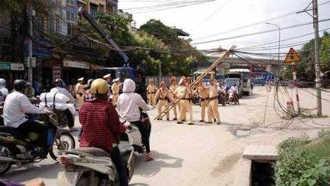 Hơn 10 chiến sỹ CSGT cùng nhau nâng dây điện, lấy đường cho dân lưu thông. Ảnh Minh Thành.