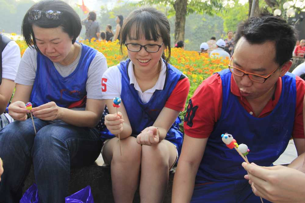 Một nhóm du khách Singapore thích thú với trò nặn tò he ở bờ Hồ. 