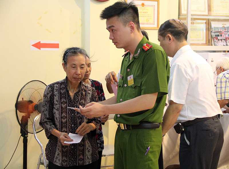 Bà Nguyễn Thị Nhâm được các cán bộ ở tổ bầu cử hướng dẫn, giúp đỡ trong quá trình bỏ phiếu (Ảnh: Phạm Thịnh)