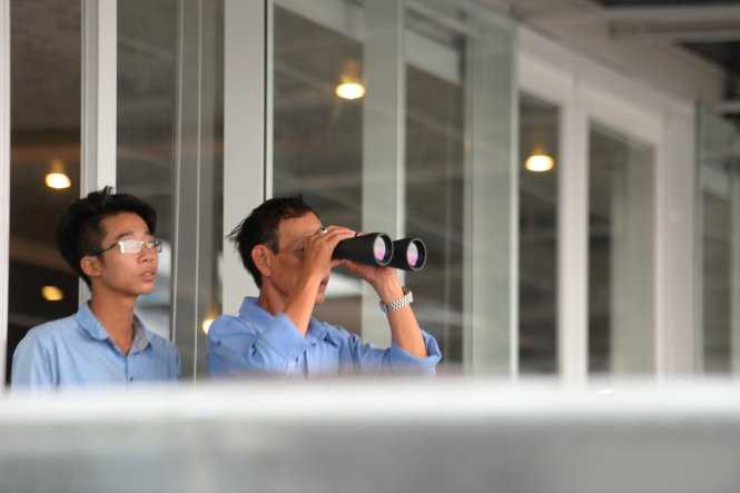 Người dân lên nhà cao tầng quan sát chiếc máy bay US Air Force (C17) - Ảnh: Hữu Khoa