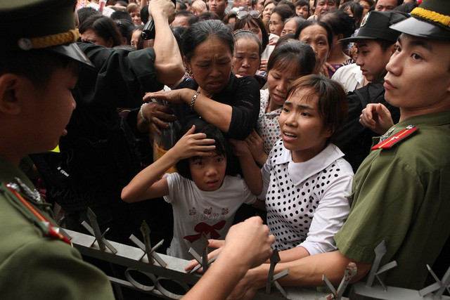 Nhiều bậc phụ huynh phải vừa chen chân đi vừa cố che chắn cho con em mình khỏi bị chèn (Ảnh: GĐ&XH)