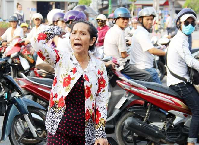 Bà Hó chạy ra đường và la hét khiến nhiều người dừng trước TAND tỉnh Sóc Trăng để xem, gây kẹt xe. Ảnh: Việt Tường.