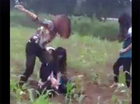 Khi nạn nhân bị ngã vật xuống ruộng ngô, người nữ đeo kính tiếp tục túm tóc, tát. Thô bạo hơn, nữ thanh niên này còn trèo lên đầu nạn nhân giẫm mấy cái