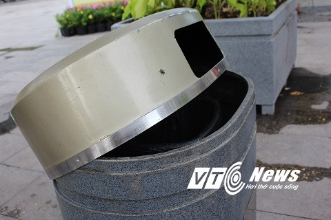 Nnhiều nắp thùng rác bị bật ra khỏi miệng khiến rác cung vãi mỗi khi có gió thổi