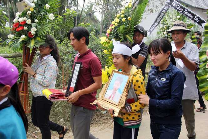 Chị gái Nhân bê di ảnh em nghẹn ngào khóc. Anh Hoàng bố của Nhân thất thần bước đi. (Ảnh: Tuổi Trẻ).