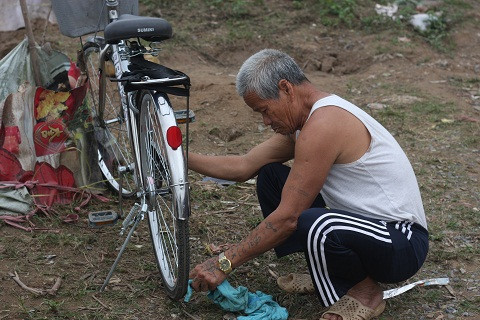 Ông Thành đang tu sửa lại chiếc xe đạp, đây là người bạn đồng hành với ông đi khắp phố phường nhặt rác - Ảnh Lâm Thắng
