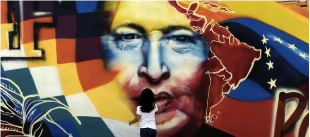 Một em bé đứng trước lá cờ in hình Tổng thống Hugo Chavez