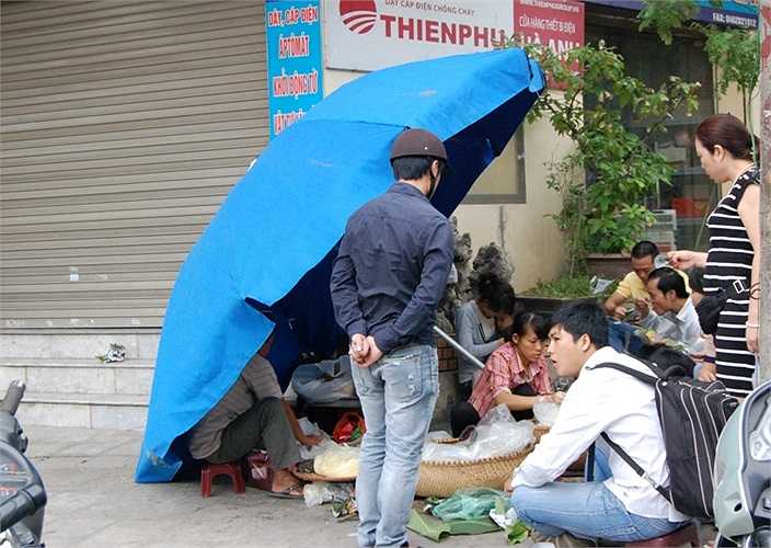 Quán xôi ven đường phải căng ô để chắn gió...