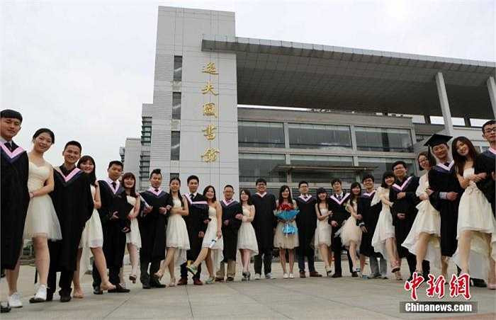 Các sinh viên xếp thành cặp, chụp ảnh trước mặt chính của trường.