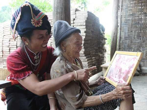 Cụ Đôi bồi hồi ngắm lại tấm hình lần cuối cùng gặp Đại tướng Võ Nguyên Giáp. (Ảnh: Hùng Võ/Vietnam+)