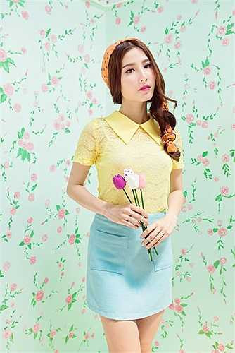 Chiếc áo màu vàng trứng đắp ren càng tôn lên vẻ yêu kiều khi được phối cùng chân váy bút chì xanh ngọc. 