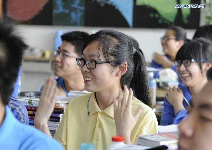 Các học sinh hăng hái giơ tay phát biểu trong lớp.