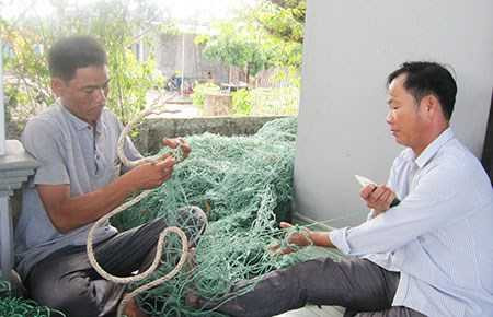 Ngư dân đang ngồi vá lại lưới bị tàu Trung Quốc cắt nát - Ảnh: Viết Long/Pháp luật TP.HCM