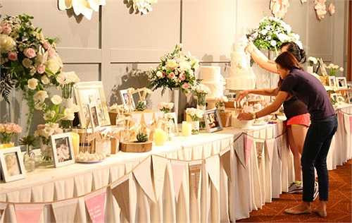 Cô chỉ đạo nhân viên hoàn chỉnh lại phần trang trí bàn tiệc, bàn tiếp tân và dàn hoa trang trí.