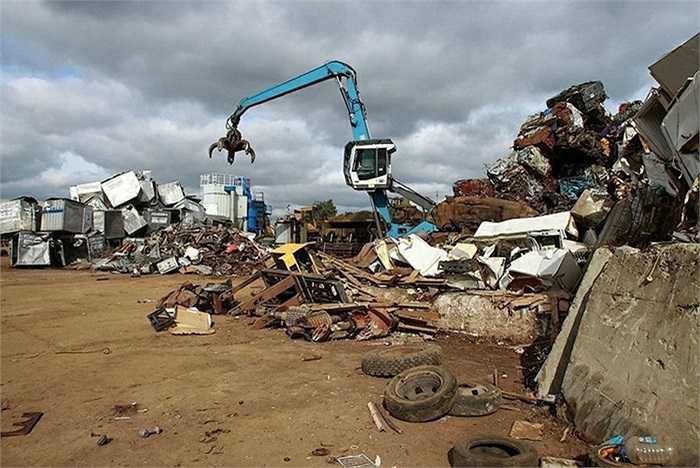 Những công nhân bãi phế thải sử dụng cần cẩu để bốc dỡ xe và di chuyển những khối kim loại khổng lồ.