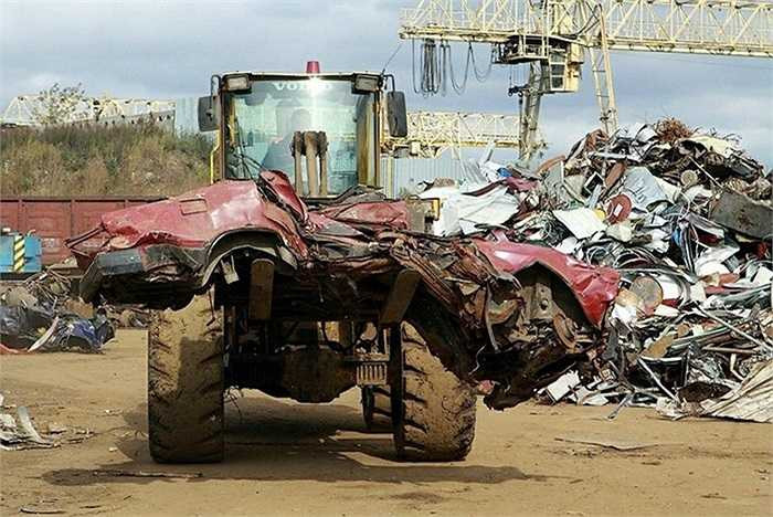 Xe bốc dỡ hàng vận chuyển một chiếc xe đã được máy cán bẹp dúm.