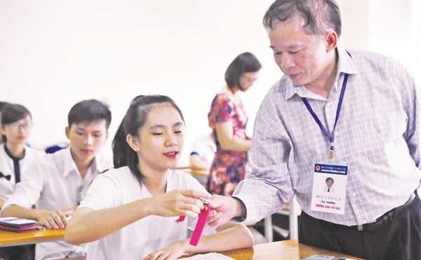 Thứ trưởng Bùi Văn Ga kiểm tra đồng hồ của một thí sinh ĐH Ngoại thương, sau đó chúc học sinh này thi tốt. Ảnh: Như Ý