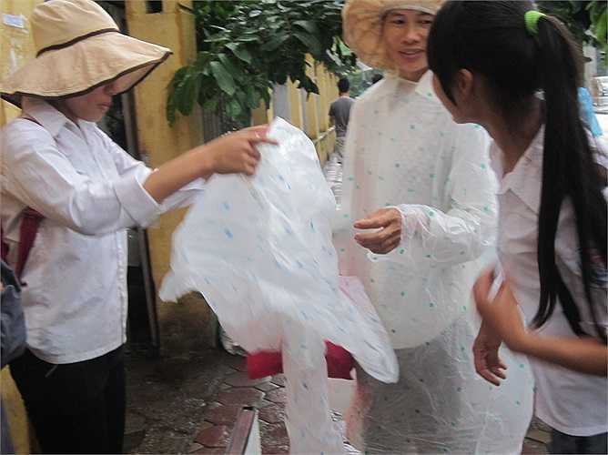 Mẹ đứng ngoài cổng trường cầm áo mưa chờ con.