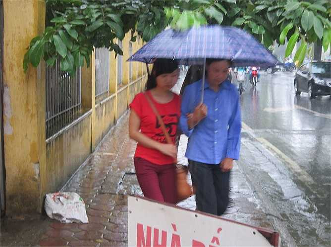 Mẹ che ô đưa con vào trường.