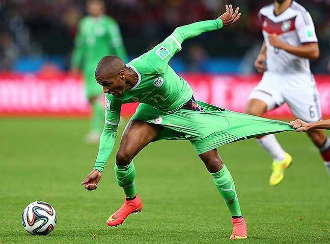 Yacini Brahimi (Algeria) tuyệt vọng đuổi theo trái bóng khi bị Philipp Lahm (Đức) kéo đến lộ cả nội y.