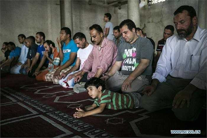 Một cậu bé chăm chú theo dõi người lớn đọc kinh trong tháng Ramadan.