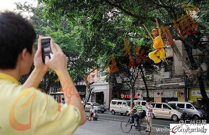 Người qua đường hiếu kỳ đua nhau chụp ảnh Tôn Ngộ Không vắt vẻo trên cây ở phố Diên Giang, Quảng Châu, tỉnh Quảng Đông, Trung Quốc
