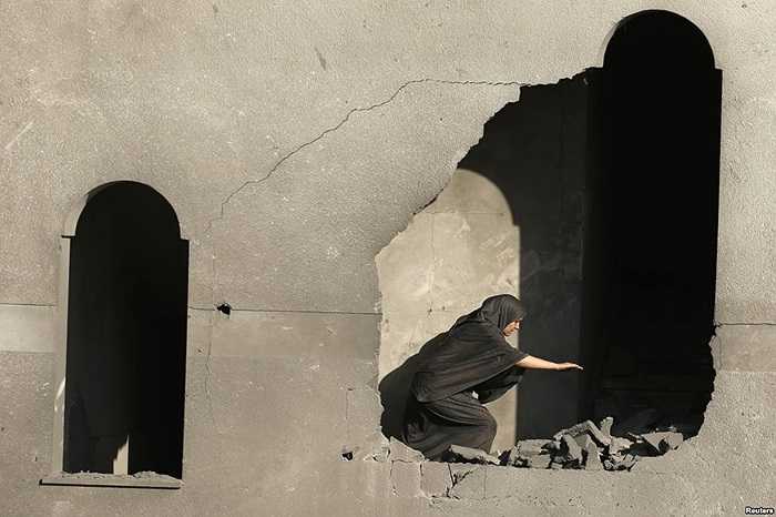 Một phụ nữ người Palestine kiểm tra ngôi nhà của mình sau vụ không kích của Israel tại thành phố Gaza
